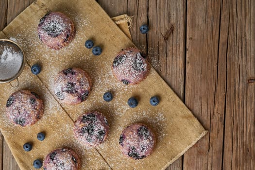 Blueberry muffin, top view, copy space. Cupcakes with berries on old rustic linen napkin, a wooden table