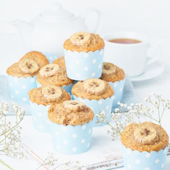Banana muffin, cupcakes in a blue cake cases paper, side view, white concrete table