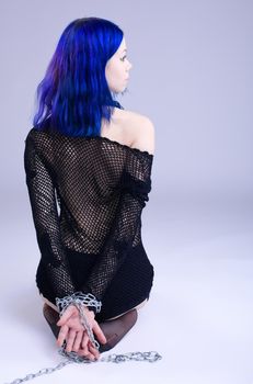 Young girl with blue hair in fetish role with chain