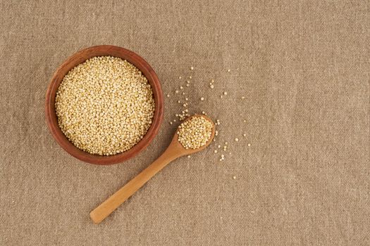 quinoa seed grain in wooden bowl and spoon on linen napkin, close up, macro