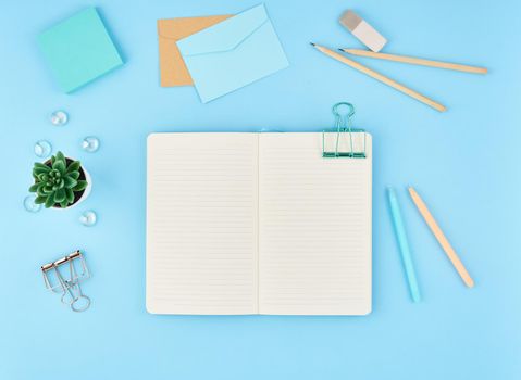 Blank notepad page for text on blue office desktop. Top view of modern bright table with notebook, envelope. Mock up, copy space.
