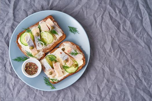 Herring smorrebrod - traditional Danish sandwiches. Black rye bread with herring on dark gray background, top view, copy space