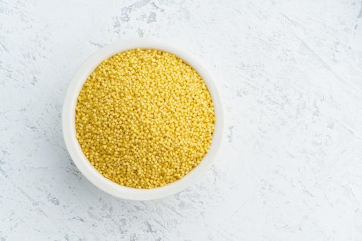 Millet, bulrush in a white bowl on white background. Lectine free, dried cereals in cup, vegan food, fodmap diet. Top view, close up.