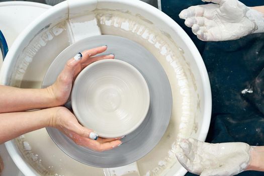 Women making ceramic pottery, concept for a workshop and master class, four hands close-up, focus on potters, palms with pottery. Two woman. Creative hobby concept, side hustle. Top view