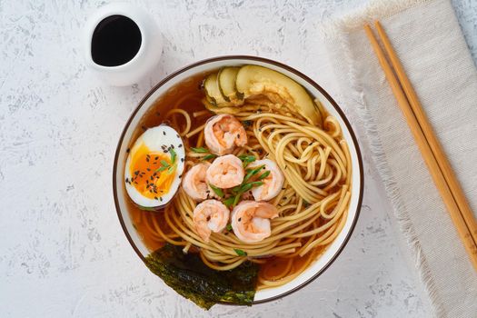 Asian soup with a noodles, ramen with shrimps, miso paste, soy sauce. White stone table