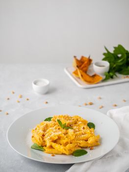 Pumpkin pasta penne with thick creamy sauce of baked squash and parmesan, side view, vertical