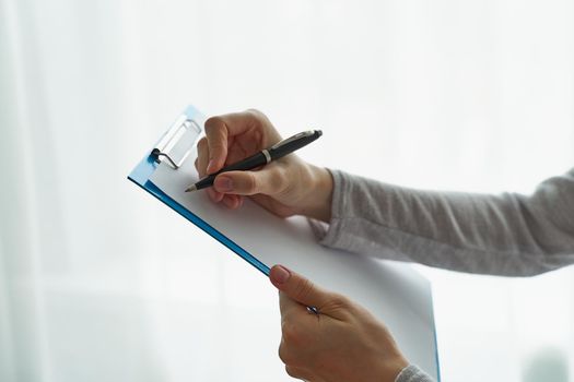 person writing on clipboard with pen, secretary or inspector idea, formal clothes