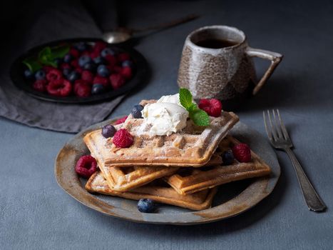 Belgian waffles with raspberries, chocolate syrup. Breakfast with tea on dark background, side view