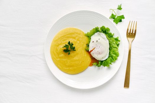 benedict egg with polenta and lettuce on white plate, copy space, healthy vegan meal