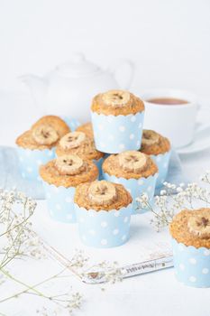 Banana muffin, cupcakes in blue cake cases paper, side view, vertcial. Morning breakfast on a white concrete table