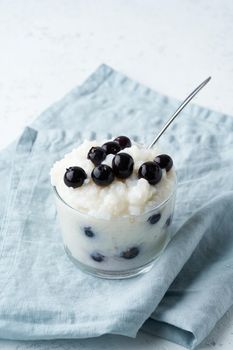 Vegan Coconut Rice Pudding with a blueberry, gluten free dessert, side view, vertical.