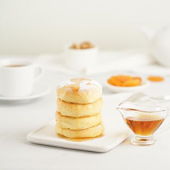 Fried cheese cakes, sweet cheese pancakes on white plate on white background. Home tea party