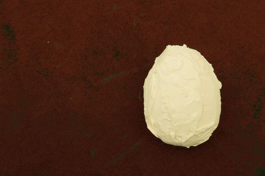 Artificial egg covered with plaster and putty on a red background