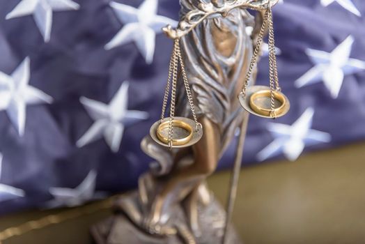 The statue of justice Themis or Iustitia, the goddess of justice blindfolded against a flag of the United States of America, as a legal concept