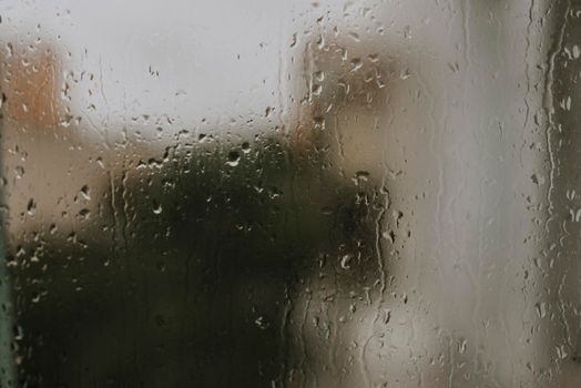 drops of rain water on the glass. drops collected on the window against the background of multi-storey buildings.