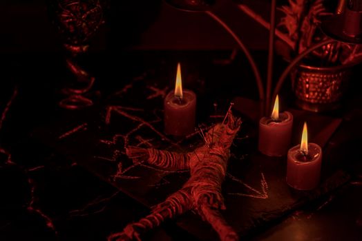 Voodoo Magic concept. Voodoo doll studded with needles with pierced rag heart on pentagram and around burning candles. Spooky or eerie magical esoteric ritua