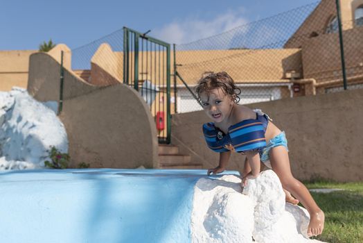 Toddler plays in the pool with children's floats. Summer arrives in the northern hemisphere