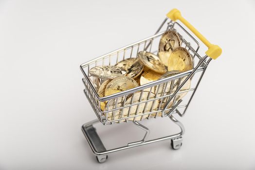 Side view of bitcoin and shopping cart on white background. Buying or selling the cryptocurrency concept. Virtual money, cryptocurrency. E-commerce concept