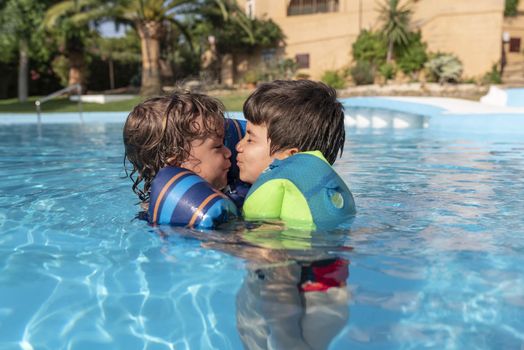 Single-parent family playing in the swimming pool. Summer arrives in the northern hemisphere