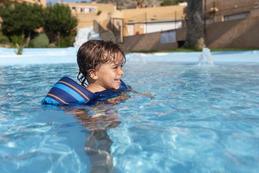 Toddler plays in the pool with children's floats. Summer arrives in the northern hemisphere