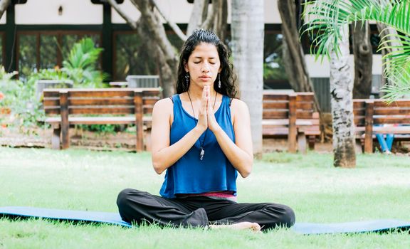 A girl sitting doing meditation yoga outdoors, Woman doing yoga outdoors, a young woman doing yoga with closed eyes.