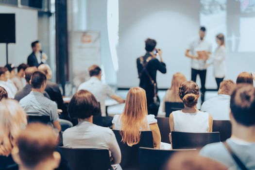 Speaker giving a talk in conference hall at business event. Rear view of unrecognizable people in audience at the conference hall. Business and entrepreneurship concept.