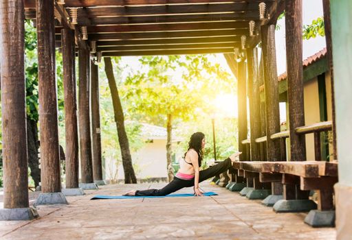Girl sitting doing split meditation yoga outdoors, woman doing side split yoga outdoors, young woman doing side split yoga