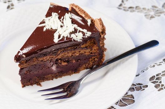 Slice of chocolate cake decorated with white chocolate flakes and blurred background. From the series "French Desserts"