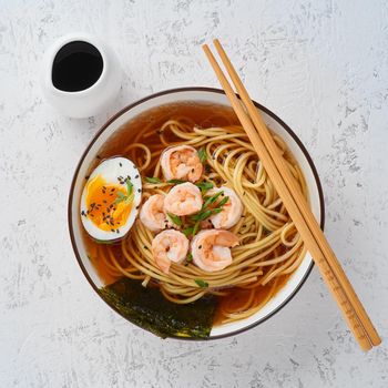 Asian soup with a noodles, ramen with shrimps, miso paste, soy sauce. White stone table, top view, close up