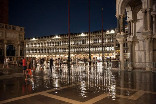 tourists witness the phenomenon of high tide in Piazza San Marco in Venice