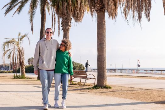 young interracial couple smiling happy while taking a walk, concept of friendship and fun in a relationship, copy space for text