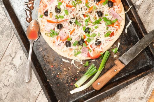 Homemade pizza on baking tray and Ingredients for cooking. From the series "Making homemade pizza"