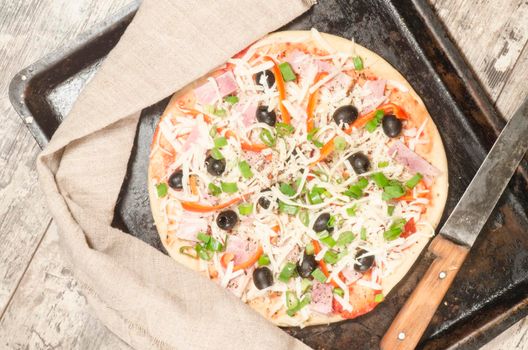 Homemade pizza on baking tray and Ingredients for cooking. From the series "Making homemade pizza"