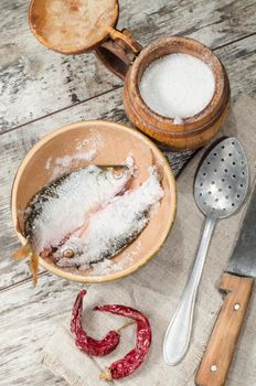 Two roaches fish in ceramic bowl with salt., near the old cutlery. From the series "Still Life with fresh fish"