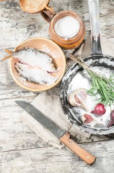 Two roaches fish in ceramic bowl with salt, near the old cutlery. From the series "Still Life with fresh fish"