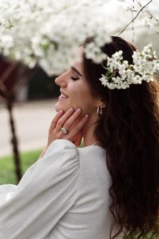 Lovely girl near blooming trees in the park. Outdoor walking in at sunny day. Lifestyle of young woman.