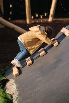 Little girl climbs up the hill on playground. Lot of enegry.