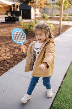 Cute little girl playing badminton in little kids city. Toy city for children.