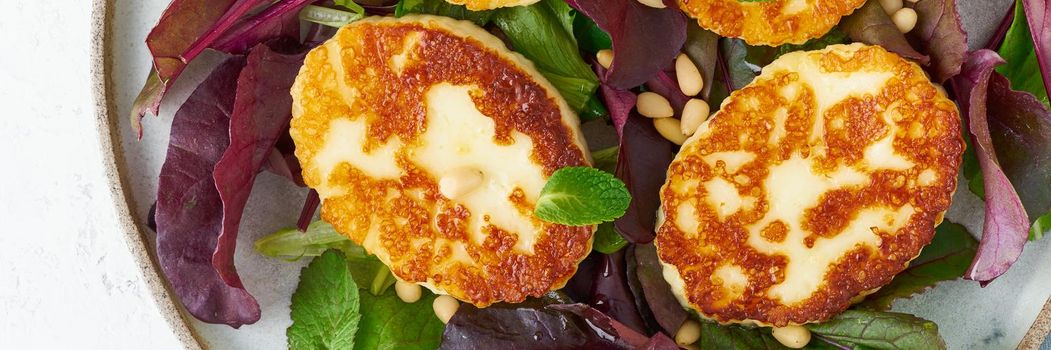 Cyprus fried halloumi with salad mix, beet tops. Lchf, pegan, fodmap, paleo, scd, keto, ketogenic diet. Balanced food, clean eating recipe. Top view, a white background, long width banner