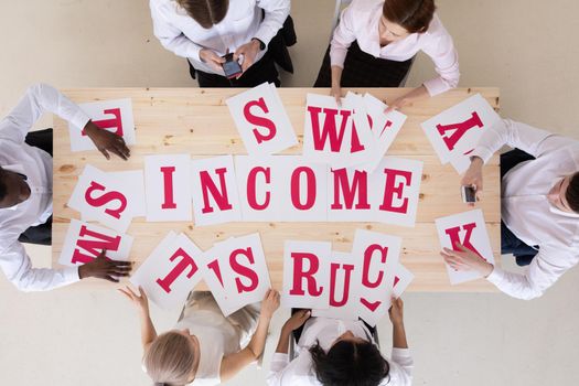 Top view of business people in formal wear sitting in boardroom at desk and merging INCOME word of letters