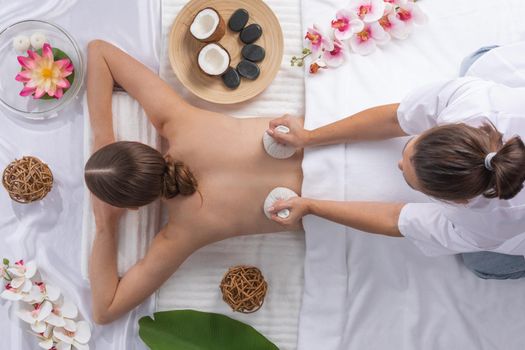 Woman at spa thai massage top view, beauty treatments concept. Orchid and lotus flowers coconut stones and herb pouches
