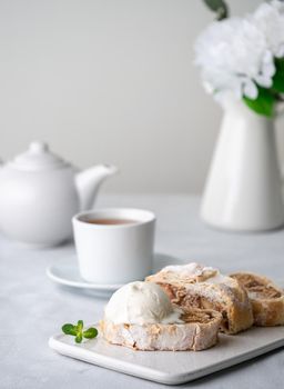 Apple strudel with ice cream and cinnamon. Baked cake and tea, delicious dessert on the table. Side view, vertical