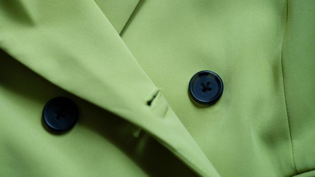 Green stylish suit with black buttons closeup.