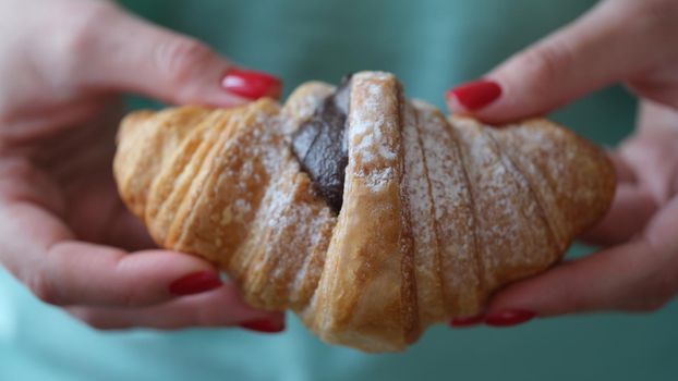 Person holds fresh tasty croissant with chocolate. Freshly made croissant recipe for healthy eating concept. Ingredients for French Baking.