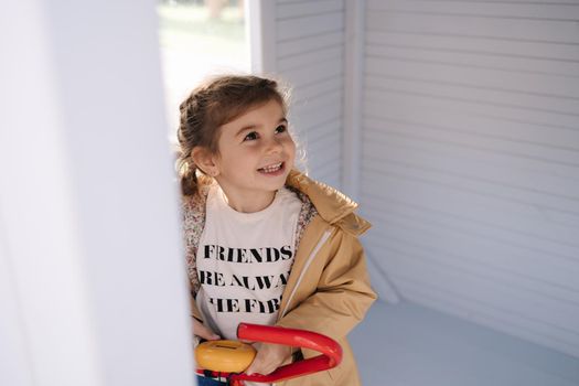 Happy little girl have sports in a toy gym. Liliput fitness center. Cute girl sits on children exercise bike and smile.