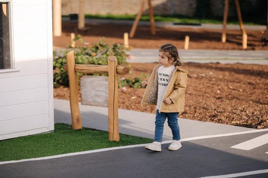 Back view of little girl walking in little kids city. Toy city for children outdoors. Road for walking.