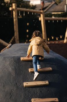 Little girl climbs up the hill on playground. Lot of enegry.