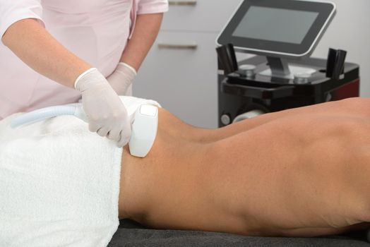 Laser hair removal on mans back. therapist in a pink t-shirt