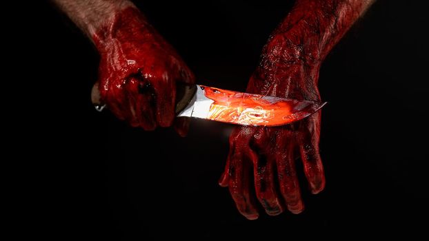 Man holding knife with bloody hand on black background