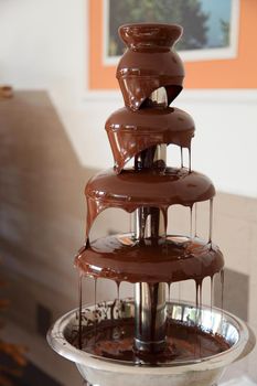 Chocolate fondue fountain with marshmallow being dipped.